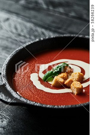 Tomato soup with cream on black wooden background. 58266239