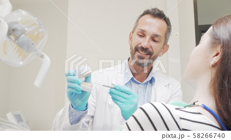 Experienced male dentist talking to his female patient Experienced male dentist talking to his female patient 58266740