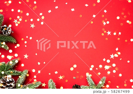 Christmas composition of fir branches and cones with shiny confetti on a red background. Christmas composition of fir branches and cones with shiny confetti on a red background. 58267499
