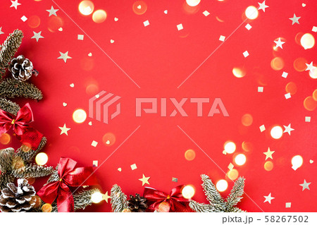 Christmas composition of fir branches and cones with shiny confetti on a red background. 58267502