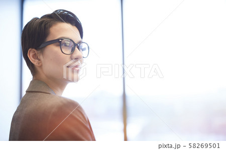 Smiling Young Businesswoman Standing by Window 58269501