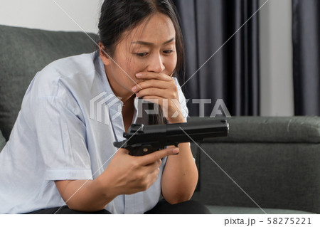 Depressed middle-aged women holding a gun in 58275221
