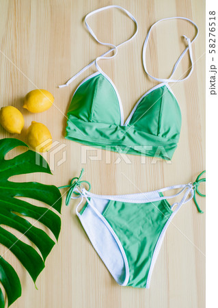 Bright trendy bikini on a wooden background with yellow lemons and tropical green leaves. Fashionable beachwear. Bright trendy bikini on a wooden background with yellow lemons and tropical green leaves. Fashionable beachwear. 58276518