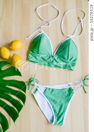 Bright trendy bikini on a wooden background with yellow lemons and tropical green leaves. Fashionable beachwear. 58276519