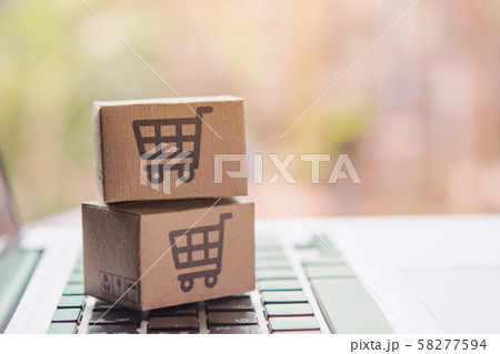 Paper cartons or parcel with a shopping cart logo on a laptop keyboard. Shopping service Paper cartons or parcel with a shopping cart logo on a laptop keyboard. Shopping service 58277594