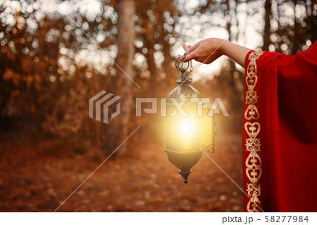 Woman holding a lantern with a candle. 58277984