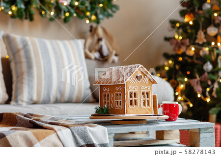 Christmas morning in the bright living room. Homemade gingerbread house on background room decorated 58278143
