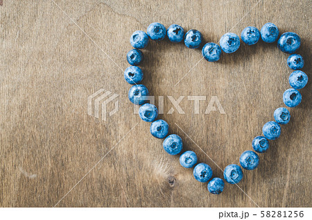 Fresh organic blueberries in form of heart on wooden background. Fresh organic blueberries in form of heart on wooden background. 58281256