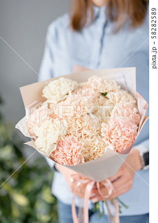Mono bouquet. Bunch of carnation flowers pastel color. Spring bunch in woman hand. Present for 58282589