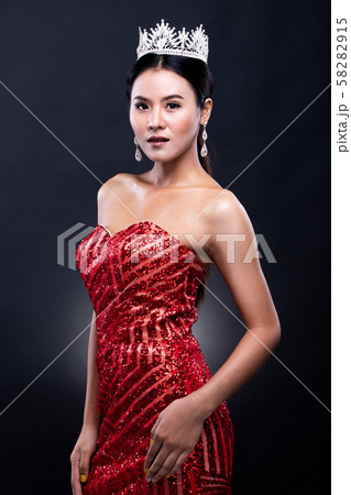Portrait of Miss Pageant Beauty Contest in Red sequin Evening Ball Gown long dress with sparkle light Diamond Crown, Asian Woman fashion make up black hair style, studio lighting dark background 58282915