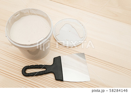 Spatula and a bucket of white putty on wooden 58284146