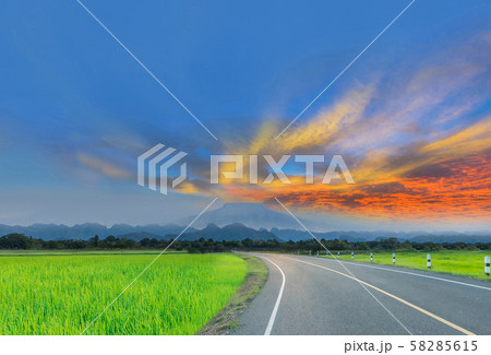 Silhouette the sunrise with the road, green paddy rice field, the beautiful sky and cloud, Thailand fuji mountain, by the beam, light and lens flare effect tone. 58285615