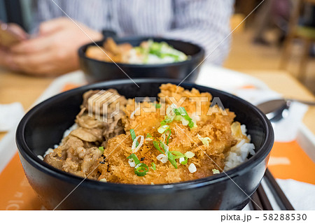 Katsudon is a popular Japanese food, a bowl of rice topped with a deep-fried pork cutlet, egg, vegetables, and condiments. Katsudon is a popular Japanese food, a bowl of rice topped with a deep-fried pork cutlet, egg, vegetables, and condiments. 58288530