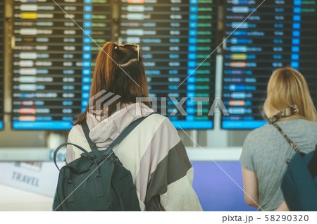 Passengers looking at the flight information board and checking their flight in international airport Passengers looking at the flight information board and checking their flight in international airport 58290320
