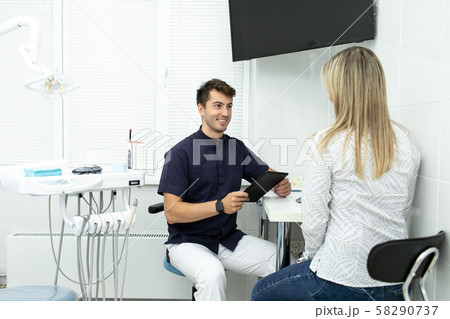 Smiling dentist discuss terms of future work with client 58290737
