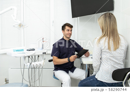 Handsome man holding tablet in hands and talking with client Handsome man holding tablet in hands and talking with client 58290744