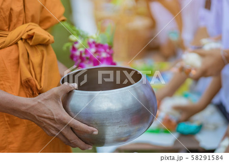Teachers and students together make merit to give food offerings to a Buddhist monk on important religious days at school. 58291584
