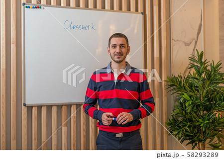 Young man standing by the chalkboard and looking 58293289