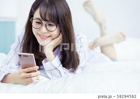 女性　スマホ　寝室　部屋着　笑顔 58294562
