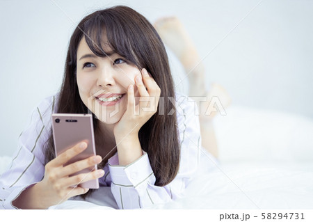 女性 スマホ 寝室 部屋着 笑顔 女性 スマホ 寝室 部屋着 笑顔 58294731