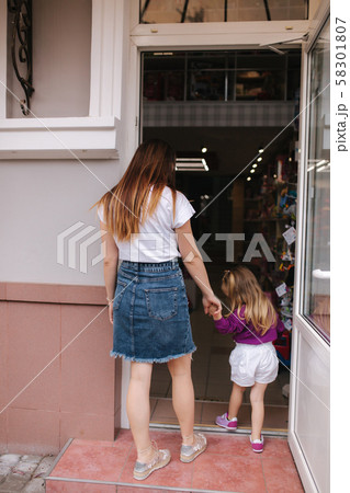 Cute little girl with her mom go into toy store. Happy kid choosing toys with mother. Mom and Cute little girl with her mom go into toy store. Happy kid choosing toys with mother. Mom and 58301807