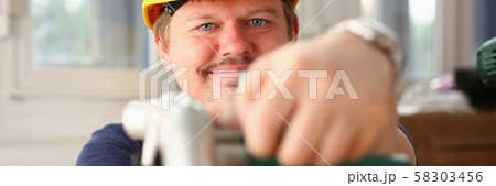 Arms of worker using electric saw closeup Arms of worker using electric saw closeup 58303456