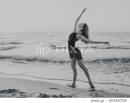 Flexible ballerina in dress dancing ballet on sea sandy beach in morning light 58309794
