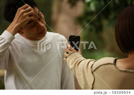 男性にスマートフォンの画面を見せる女性 男性にスマートフォンの画面を見せる女性 58309934