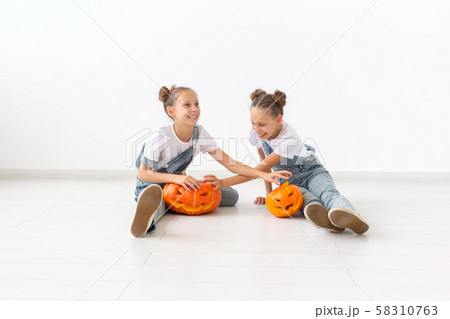 Happy Halloween, holidays and childhood concept - Cute little twins sisters girls with a pumpkins Happy Halloween, holidays and childhood concept - Cute little twins sisters girls with a pumpkins 58310763