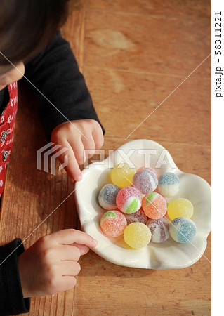 和食器に盛ったカラフルな飴玉と小さな女の子の手 和食器に盛ったカラフルな飴玉と小さな女の子の手 58311221