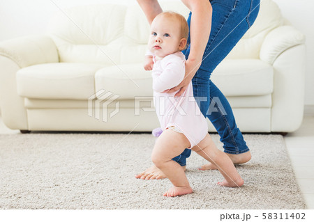 Little baby girl first steps with the help of mom 58311402
