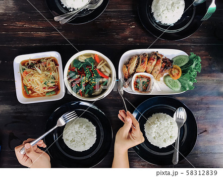 People eating Thai food on a brown wooden table. People eating Thai food on a brown wooden table. 58312839