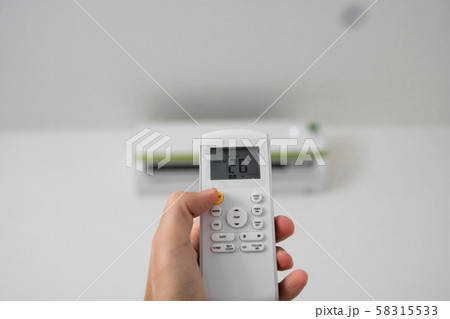 Man's hand using remote controler. Hand holding rc and adjusting temperature of air conditioner 58315533