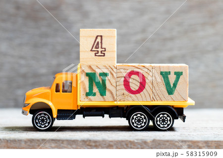 Truck hold letter block in word 4nov on wood background Truck hold letter block in word 4nov on wood background 58315909