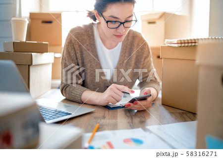 Woman is working at warehouse for online store. Woman is working at warehouse for online store. 58316271