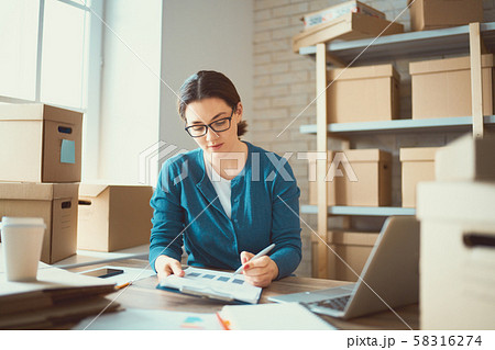 Woman is working at warehouse for online store. Woman is working at warehouse for online store. 58316274