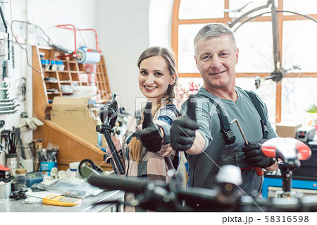 Two bike mechanics in their workshop having a successful day Two bike mechanics in their workshop having a successful day 58316598