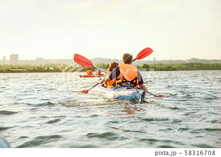 Happy friends kayaking on river with sunset on the background 58316708