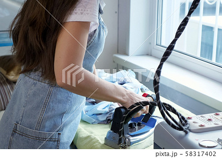 Seamstress ironing details of clothes in sewing workshop of tailoring business. 58317402