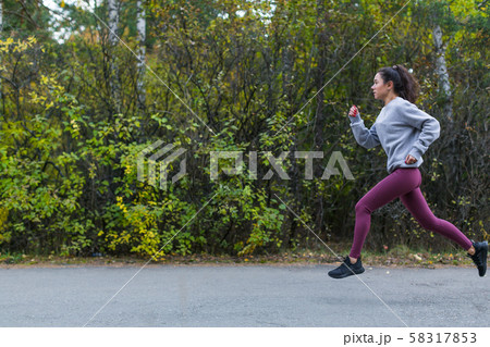 Side view of a running woman in autumn city park 58317853