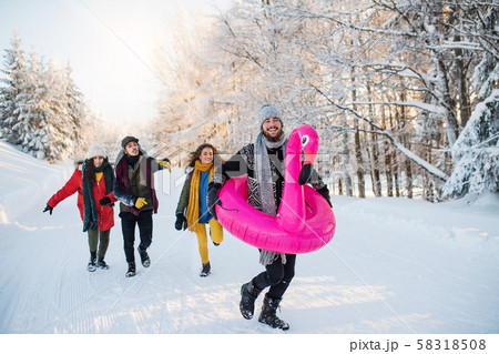A group of young friends on a walk outdoors in snow in winter forest. 58318508