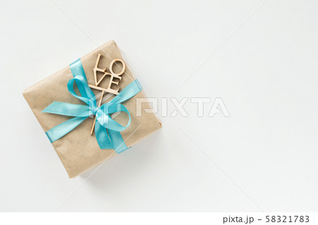 Gift box wrapped in brown paper with blue ribbon 58321783