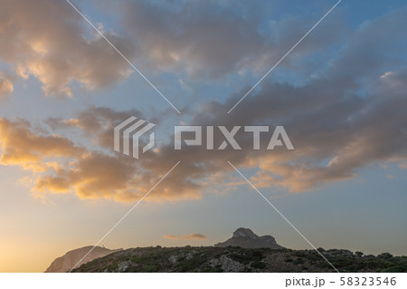 Background clouds in the sky are highlighted by the rising sun. Mountains in the background 58323546