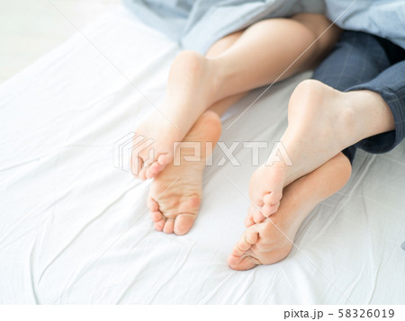 Couple lying in bed, sleeping under blanket, feet close up. Couple lying in bed, sleeping under blanket, feet close up. 58326019