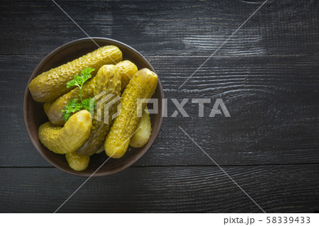 Canned vegetables cucumber in bowl on dark board. 58339433