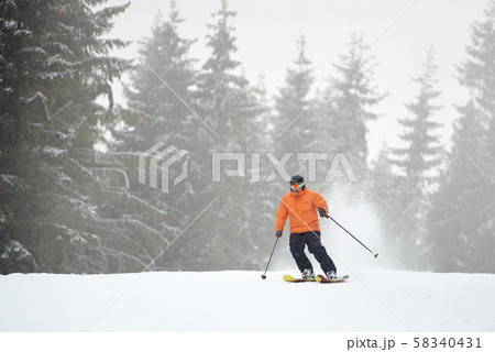 Adult male skiing during heavy snowfall. Monochrome view. Recreational outdoors sports vacation Adult male skiing during heavy snowfall. Monochrome view. Recreational outdoors sports vacation 58340431