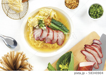 Egg noodle and pork wonton soup with red roasted pork in white bowl and seasoning on white table top view and horizontal. Egg noodle and pork wonton soup with red roasted pork in white bowl and seasoning on white table top view and horizontal. 58340904