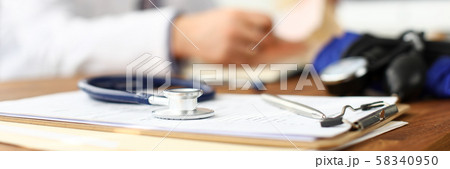 Stethoscope head lying at worktable over patient medical history paper 58340950