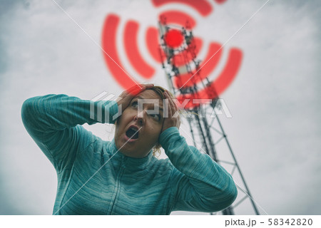 Woman is holding her head near the 5G BTS 58342820