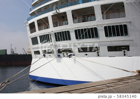 Close-up tail view of big modern white cruise ship liner morred with mooring cable at cargo port of Close-up tail view of big modern white cruise ship liner morred with mooring cable at cargo port of 58345140